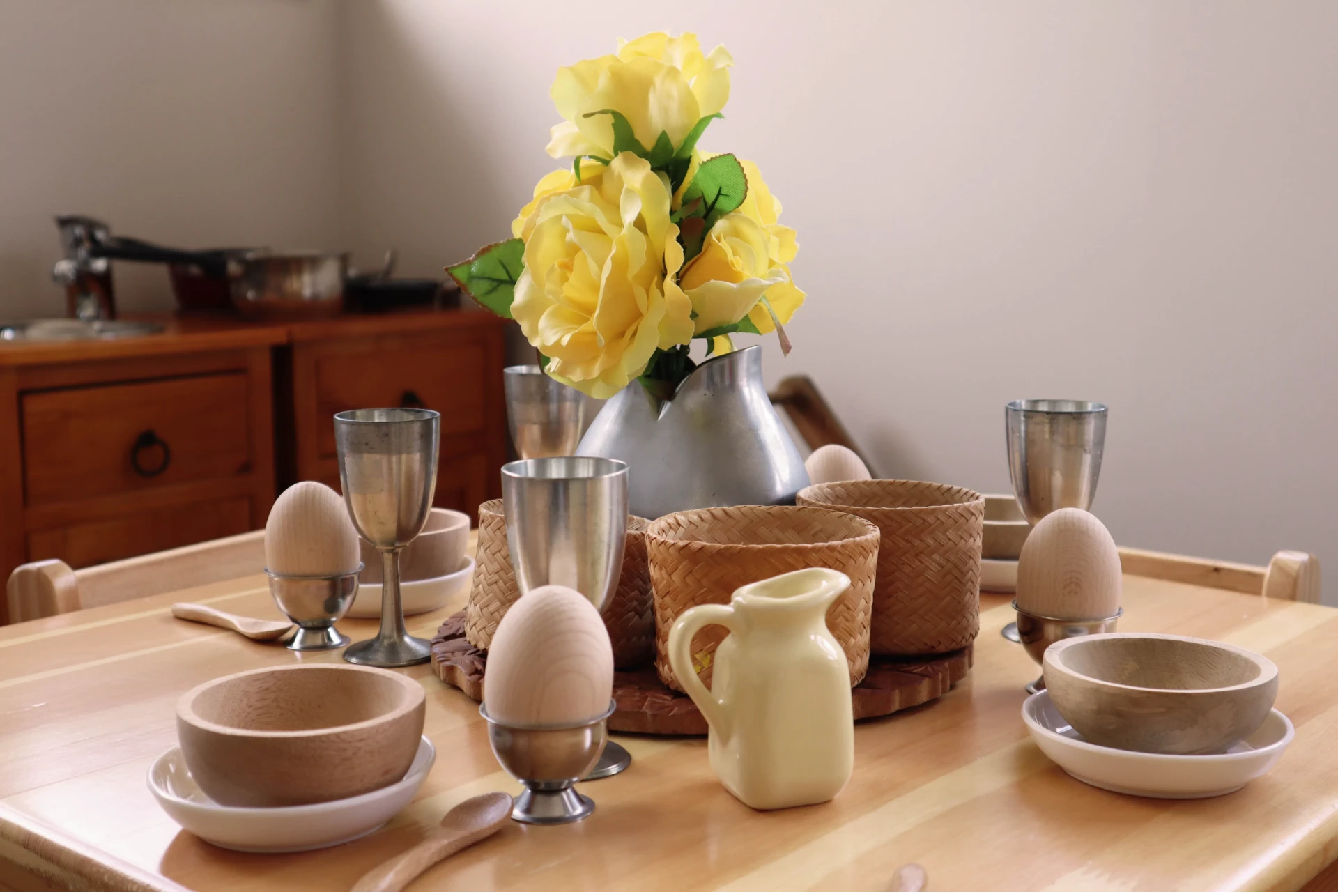 Real crockery, wooden bowls and flowers set out on a child sized table