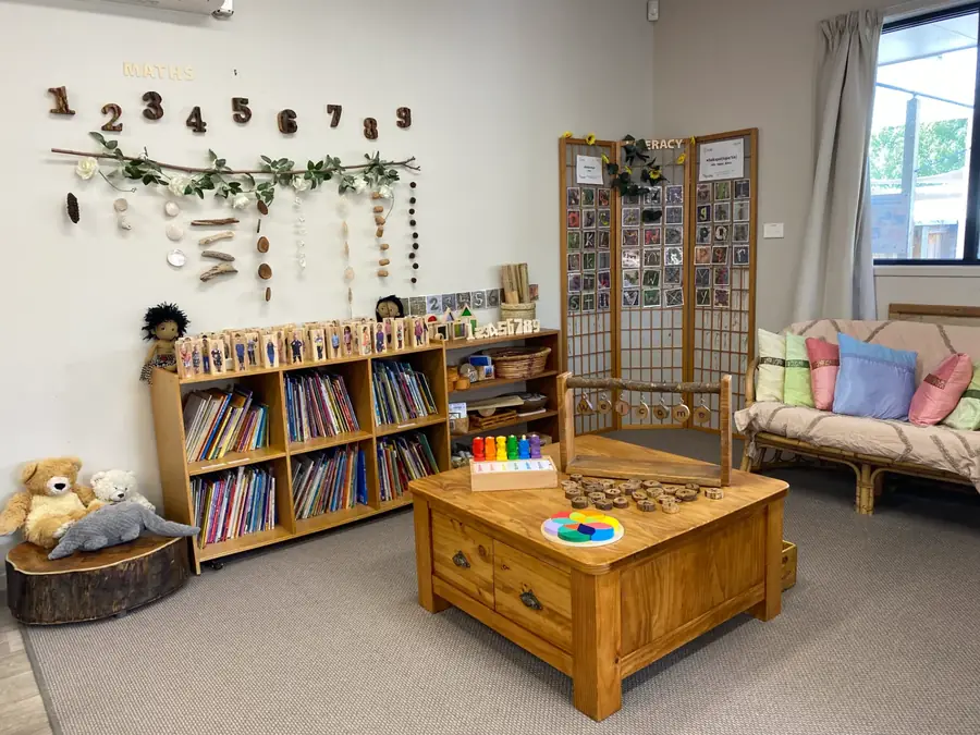 Maths and literacy corner in the Kākāpō Room with wooden numbers, natural materials, books and a cosy couch