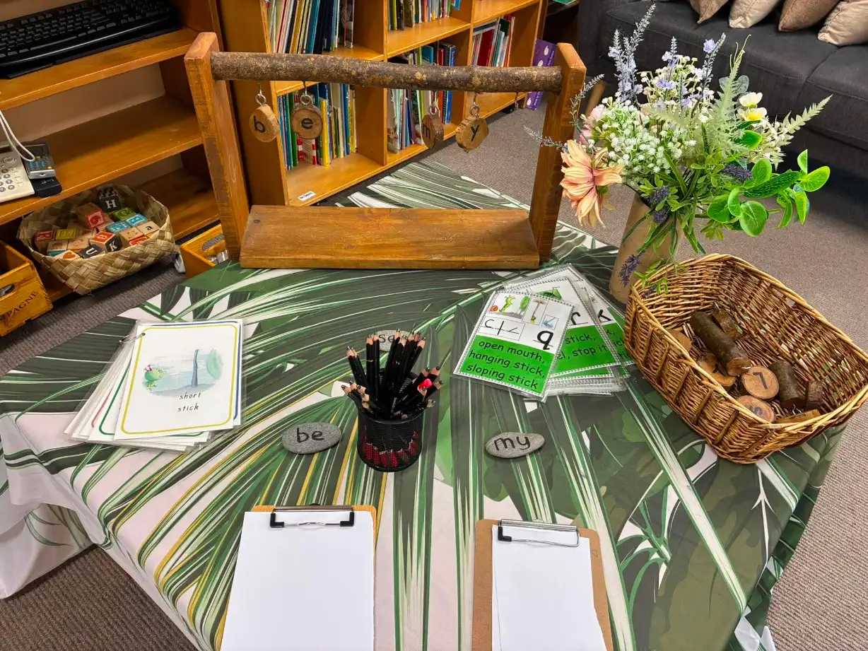 A literacy provocation table set up with letter stones, pencils and clipboards