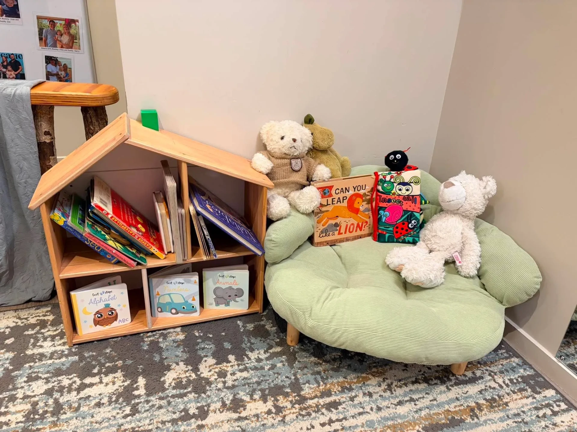 A cosy book corner in the Bee Room with a house shaped bookshelf, board books and soft toys